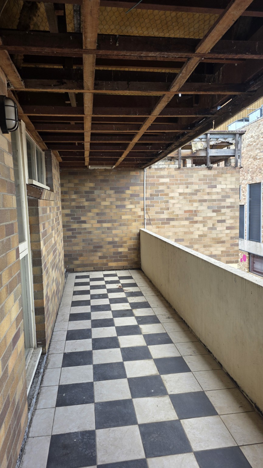 Brick verandah with ceiling lining removed, exposed timber framing and a retained tiled floor.