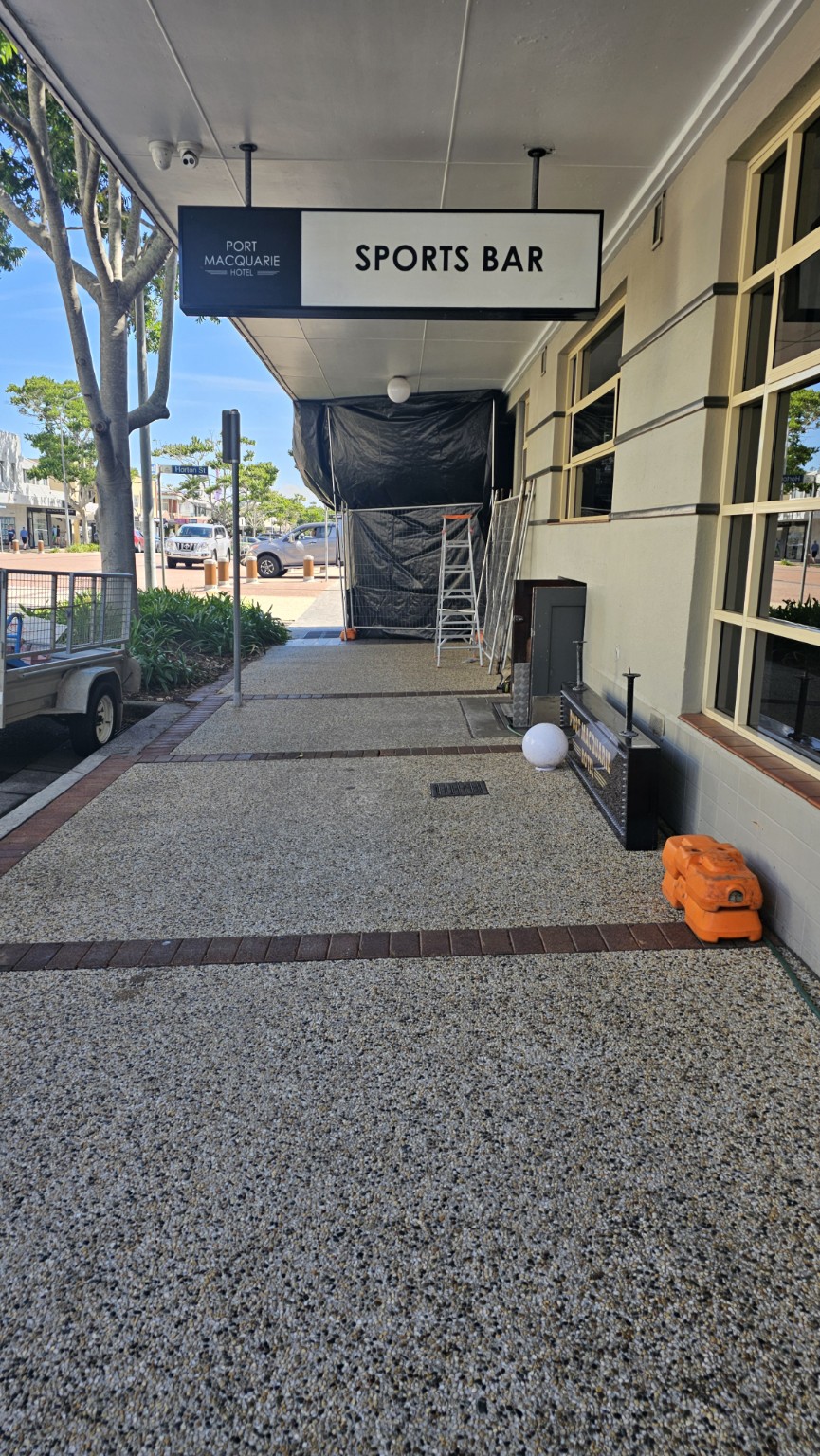 High risk external removal work screened off beside a commercial building footpath, beneath an existing verandah.
