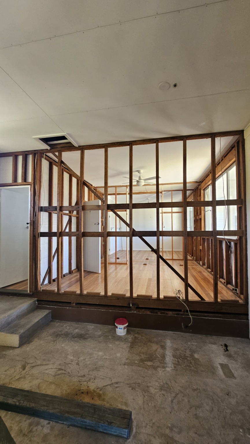 Internal wall linings removed to reveal timber studs, with timber floors and existing doors retained.