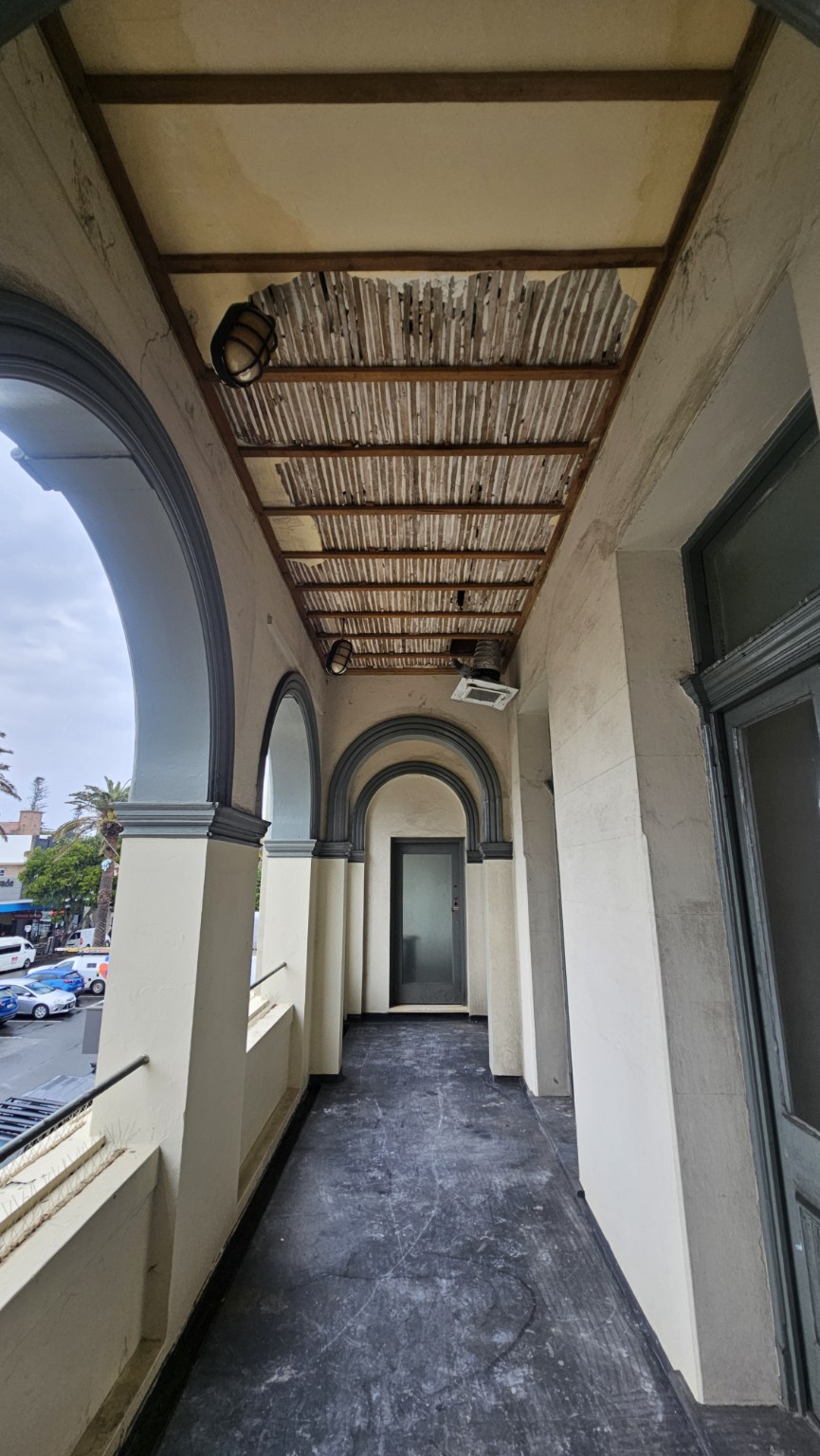 Verandah with ceiling linings removed to expose timber battens and the underside of roof sheets.